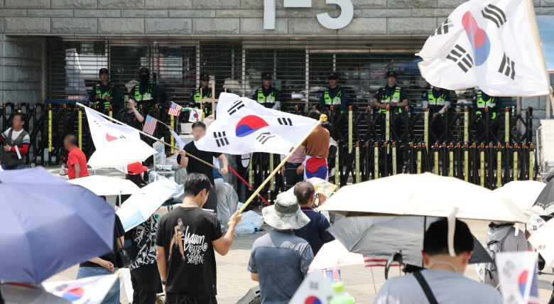 6·3 지방선거 당시 잠실 개표소로 사용된 서울 송파구 올림픽공원 핸드볼경기장 앞에서 28일 투표용지 부족 사태 규탄 봉쇄 시위 참가자들이 우산을 쓰고 구호를 외치고 있다. 연합